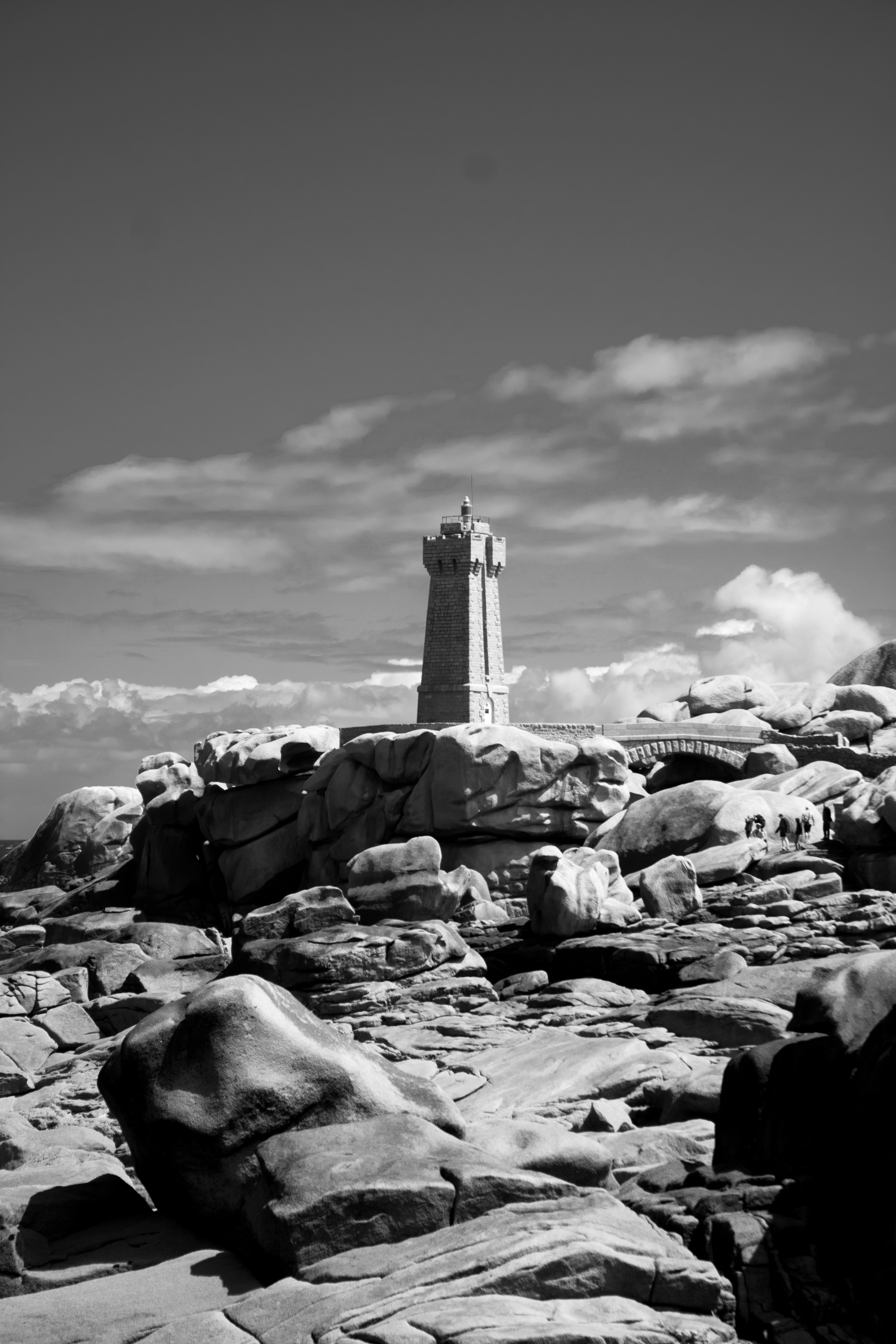 A black and white photo of a lighthouse on a rocky beach