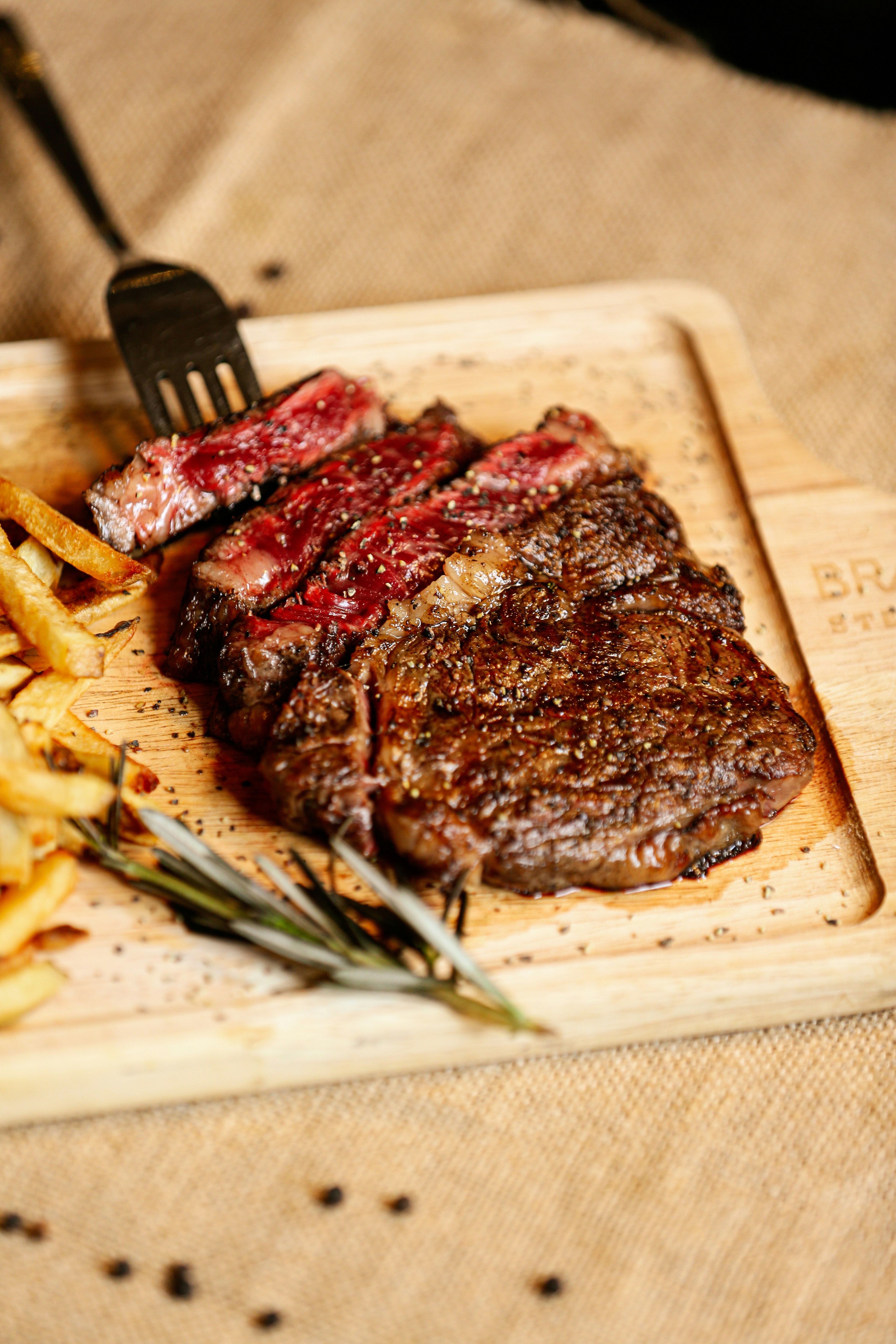 A steak and french fries on a cutting board