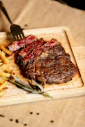 A steak and french fries on a cutting board