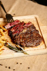 A steak and french fries on a cutting board