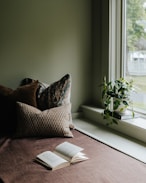 A bed with a book on top of it next to a window