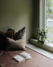 A bed with a book on top of it next to a window