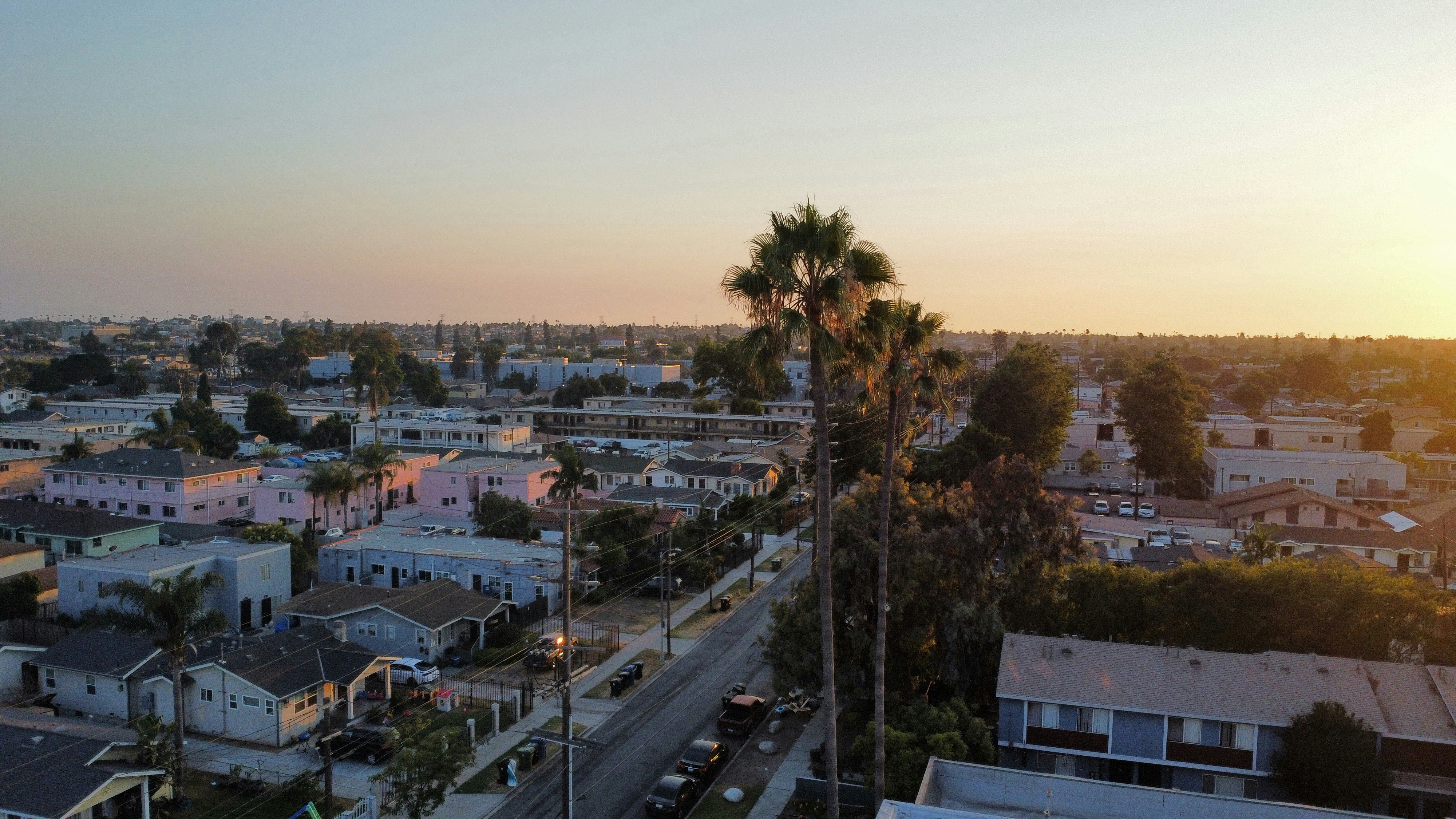 The sun is setting over a city with palm trees