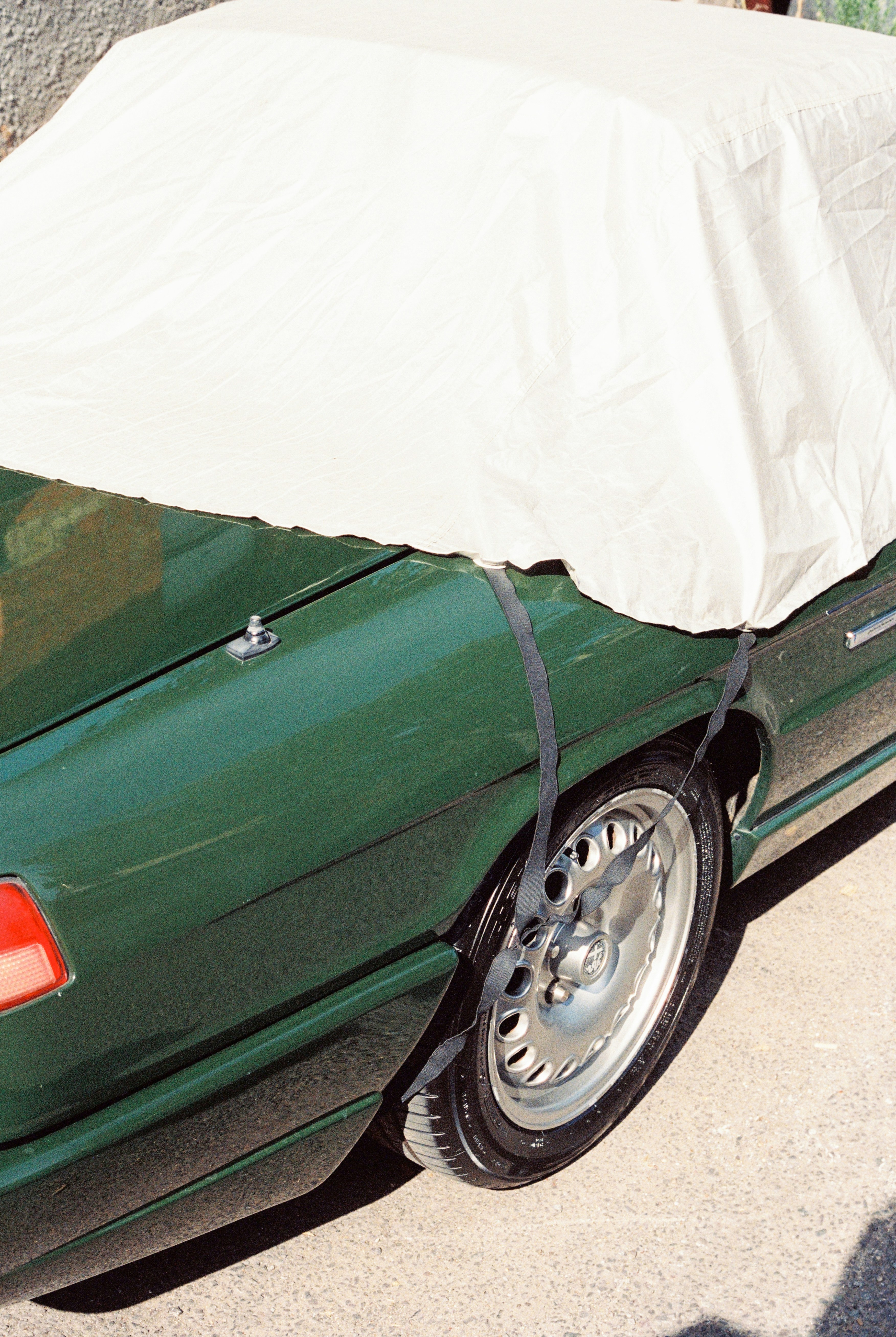 A green car with a white tarp on top of it