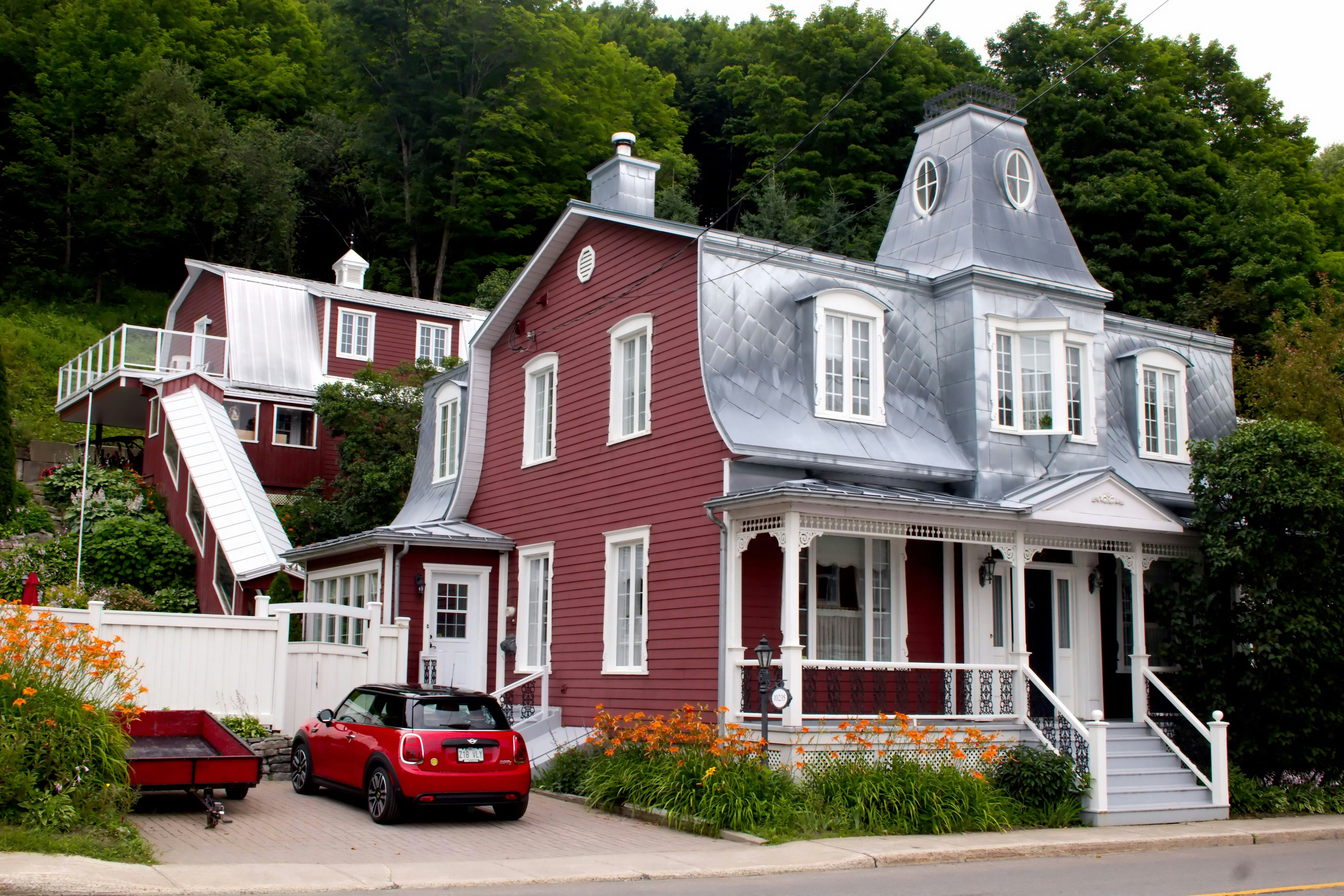 A red and white house with a red car parked in front of it