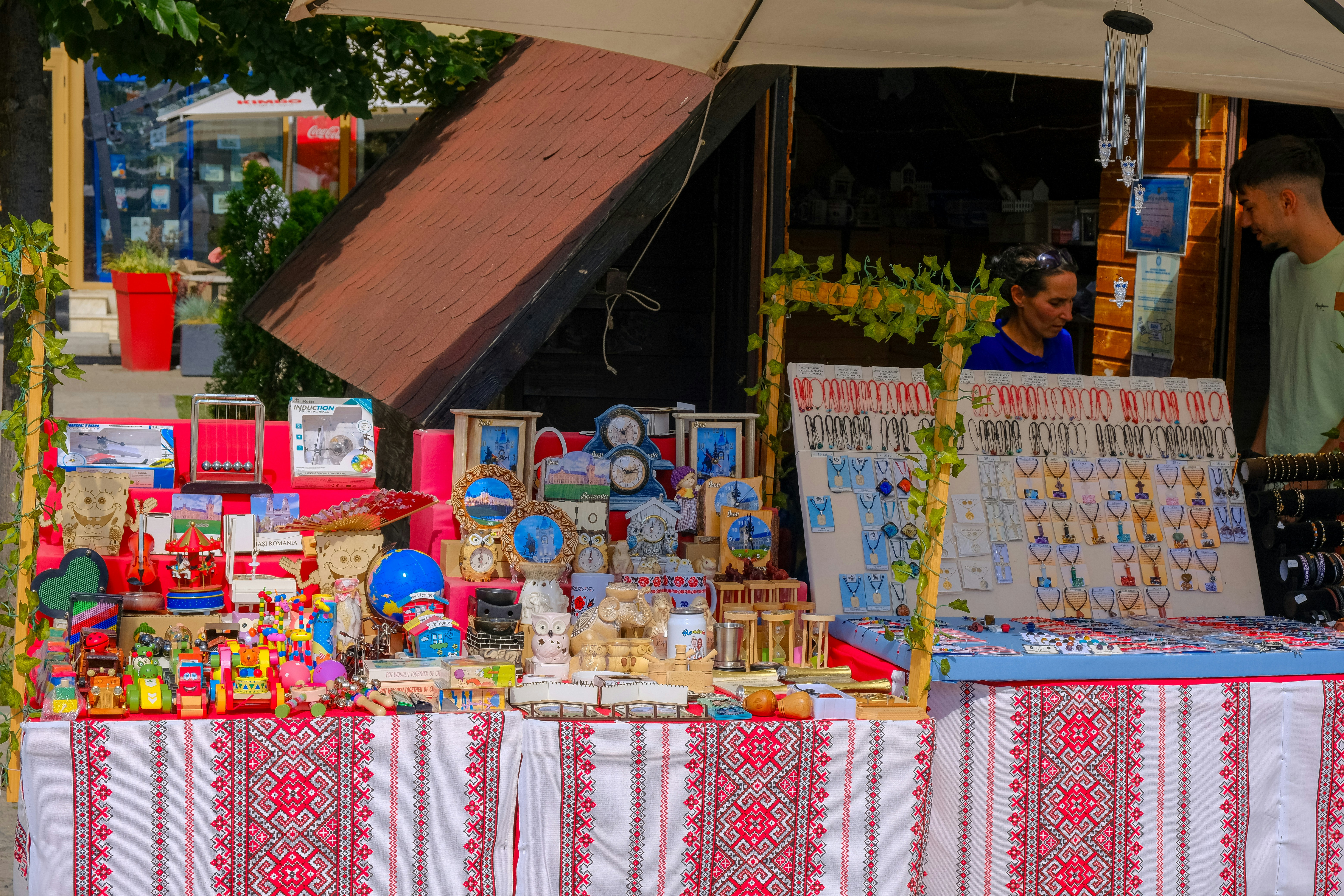 Vendor arranges handmade crafts on a market stall table.