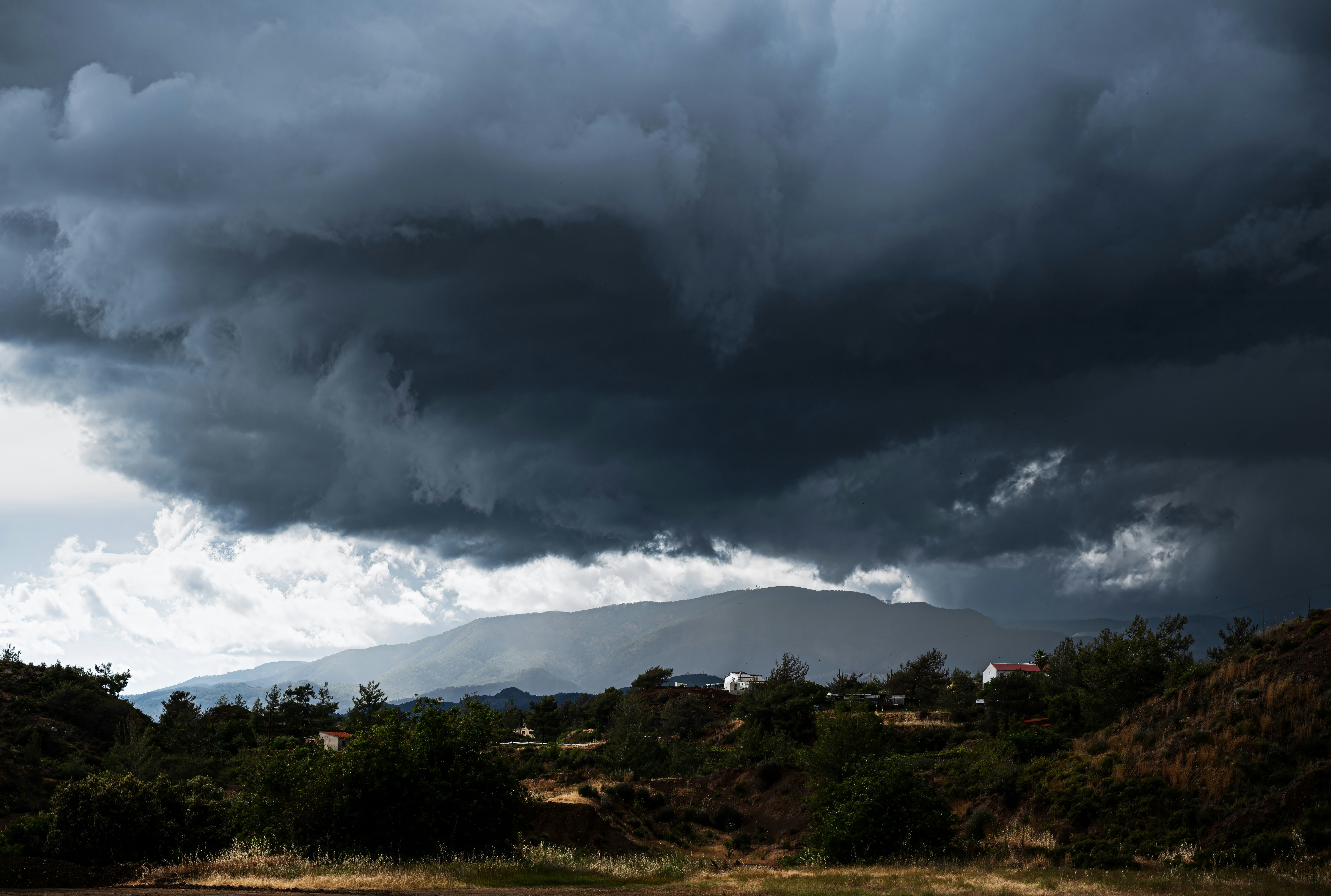 Um céu nublado sobre um campo com um cavalo em primeiro plano