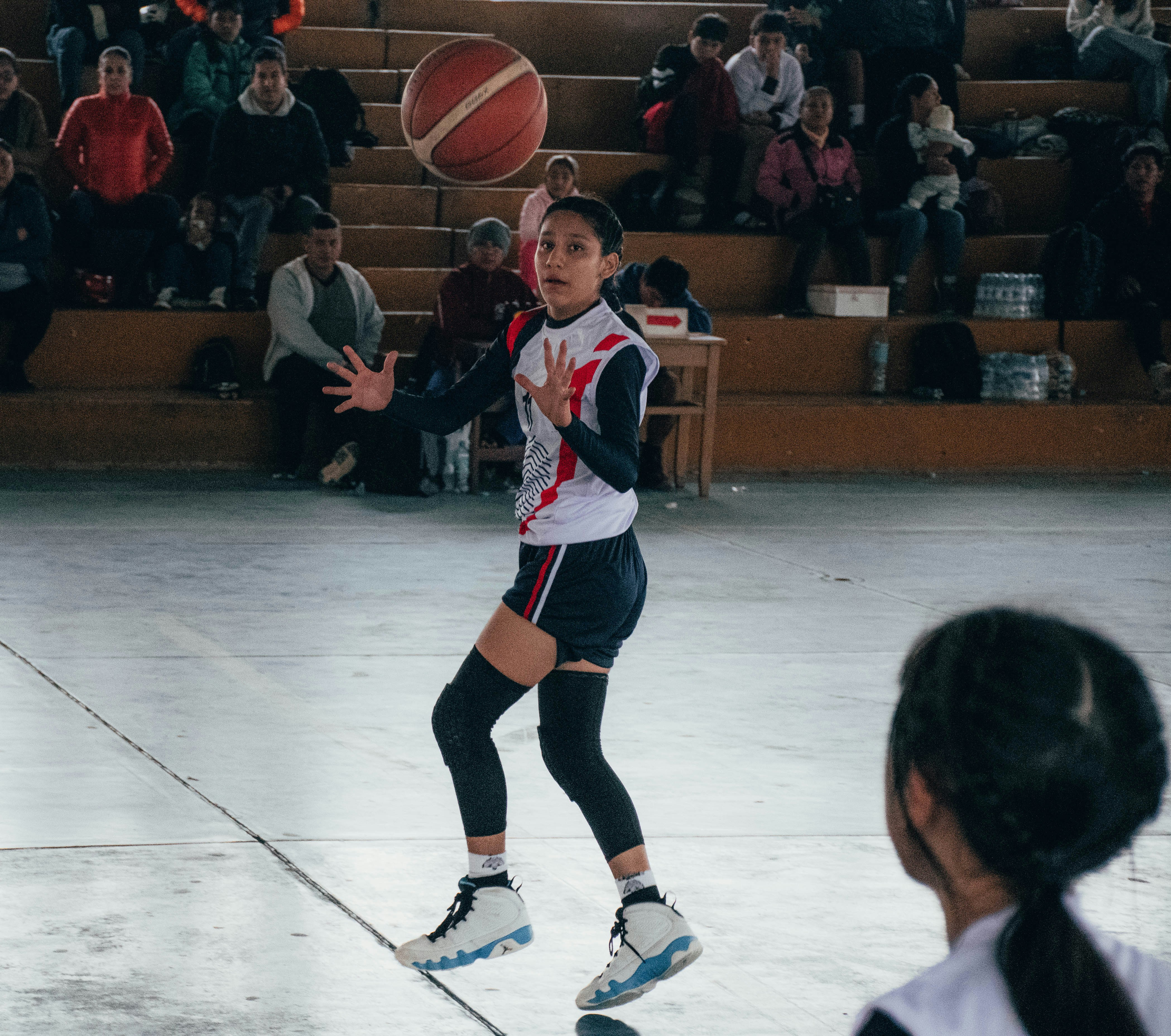 A girl is playing basketball in front of a crowd