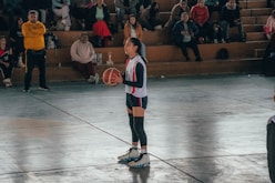 A woman standing on a basketball court holding a basketball