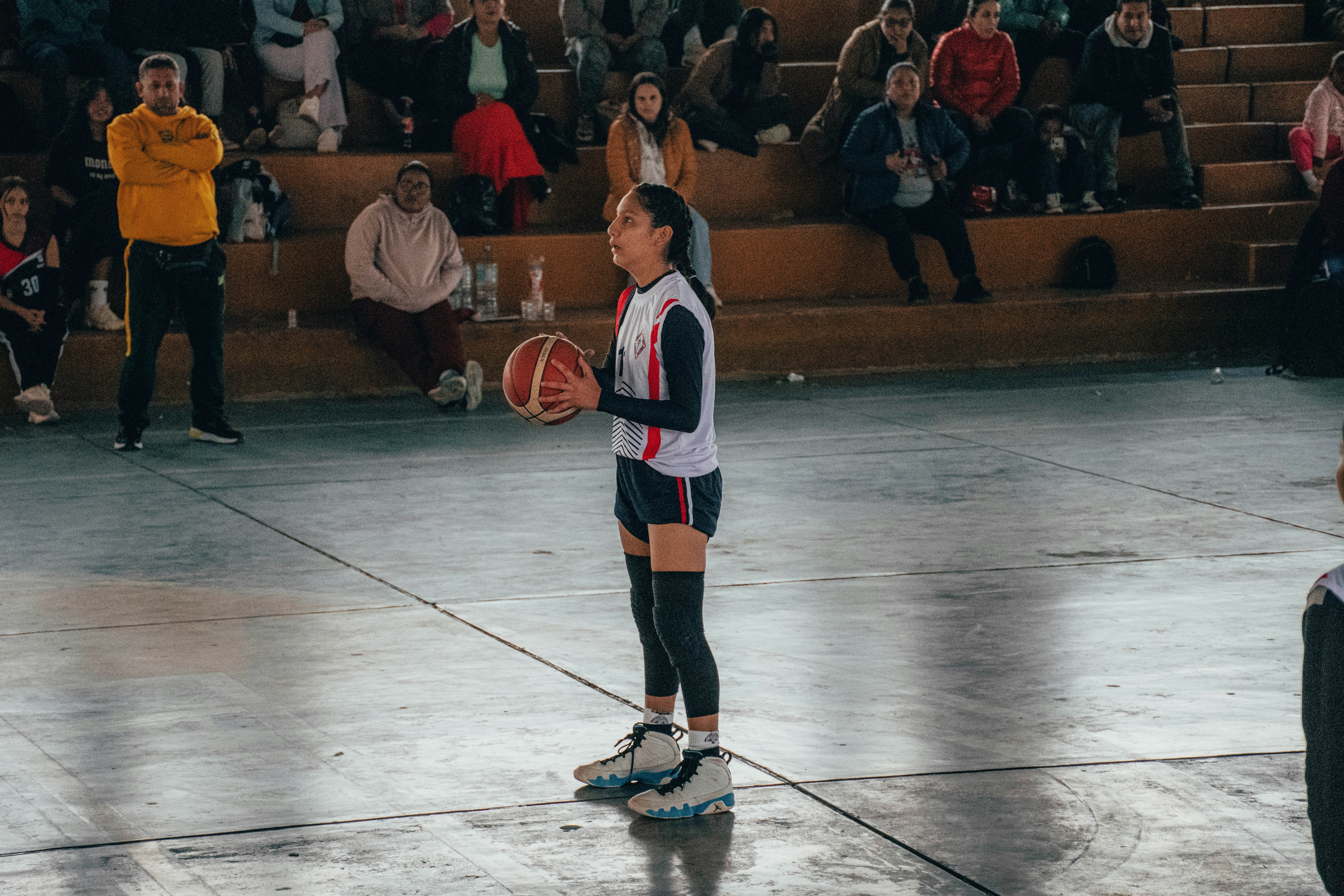A woman standing on a basketball court holding a basketball