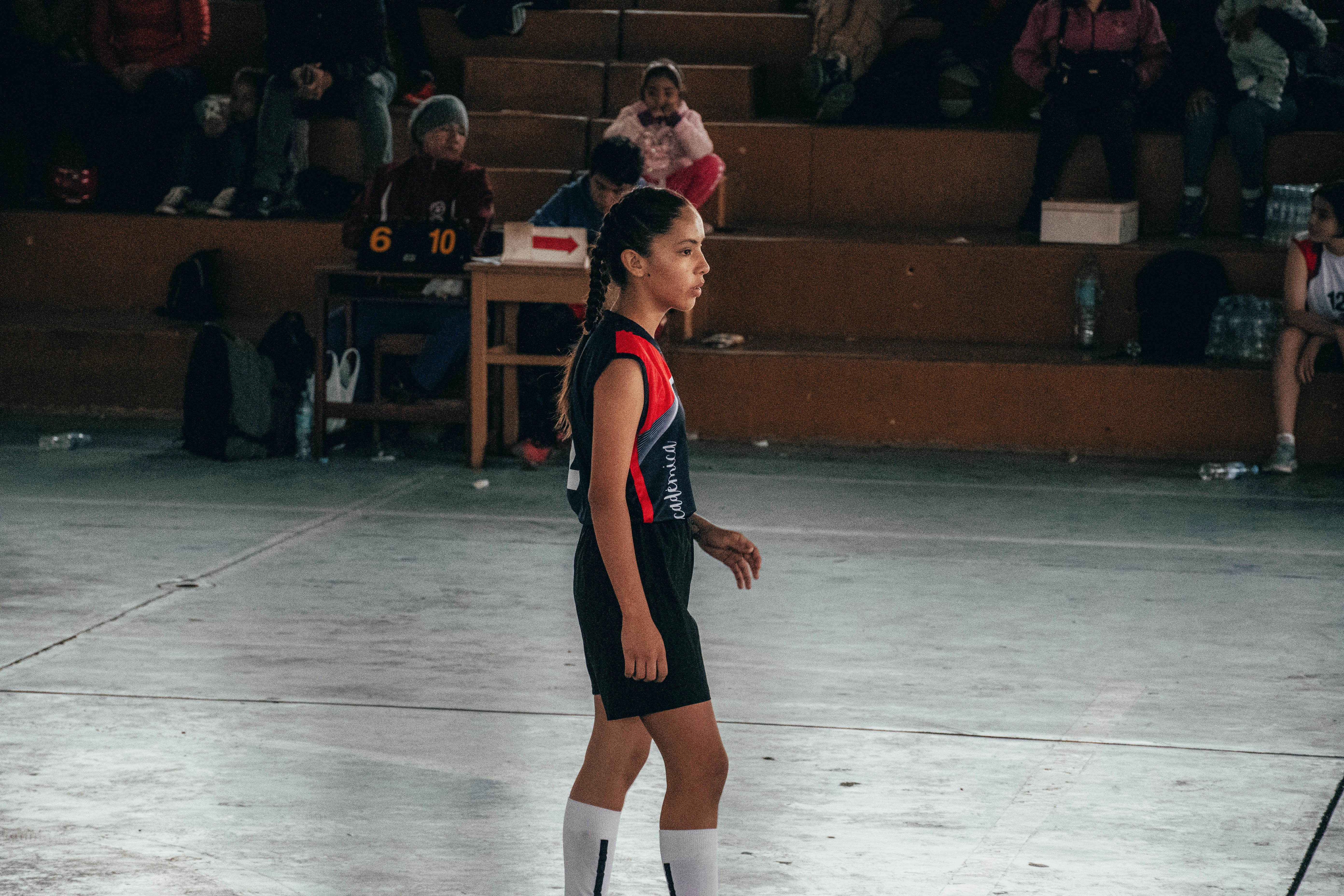 A girl in a black and red uniform is playing soccer