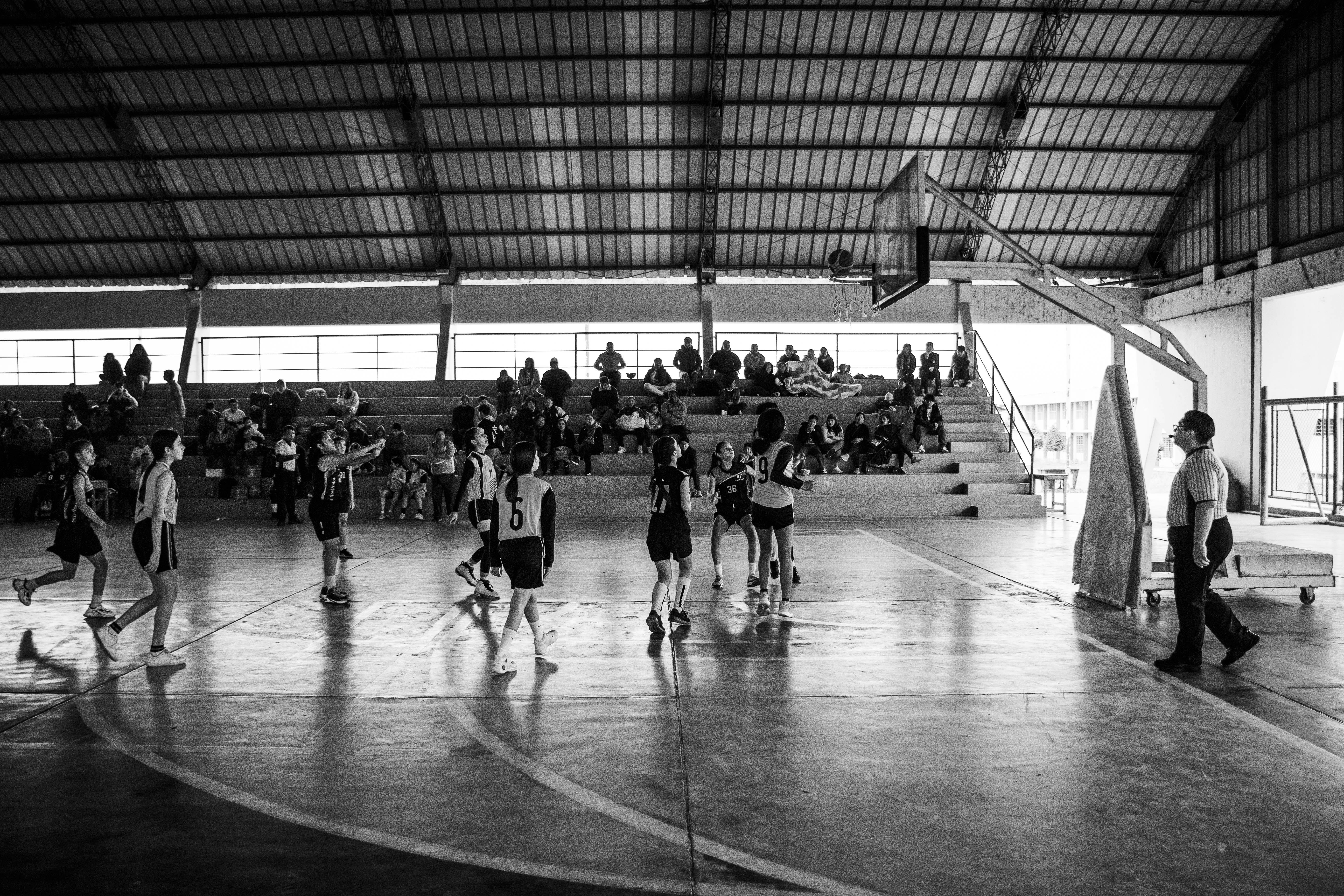A group of people playing basketball inside of a building