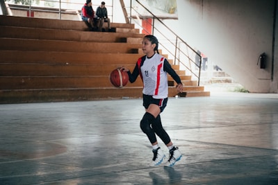 A woman dribbling a basketball in a gym