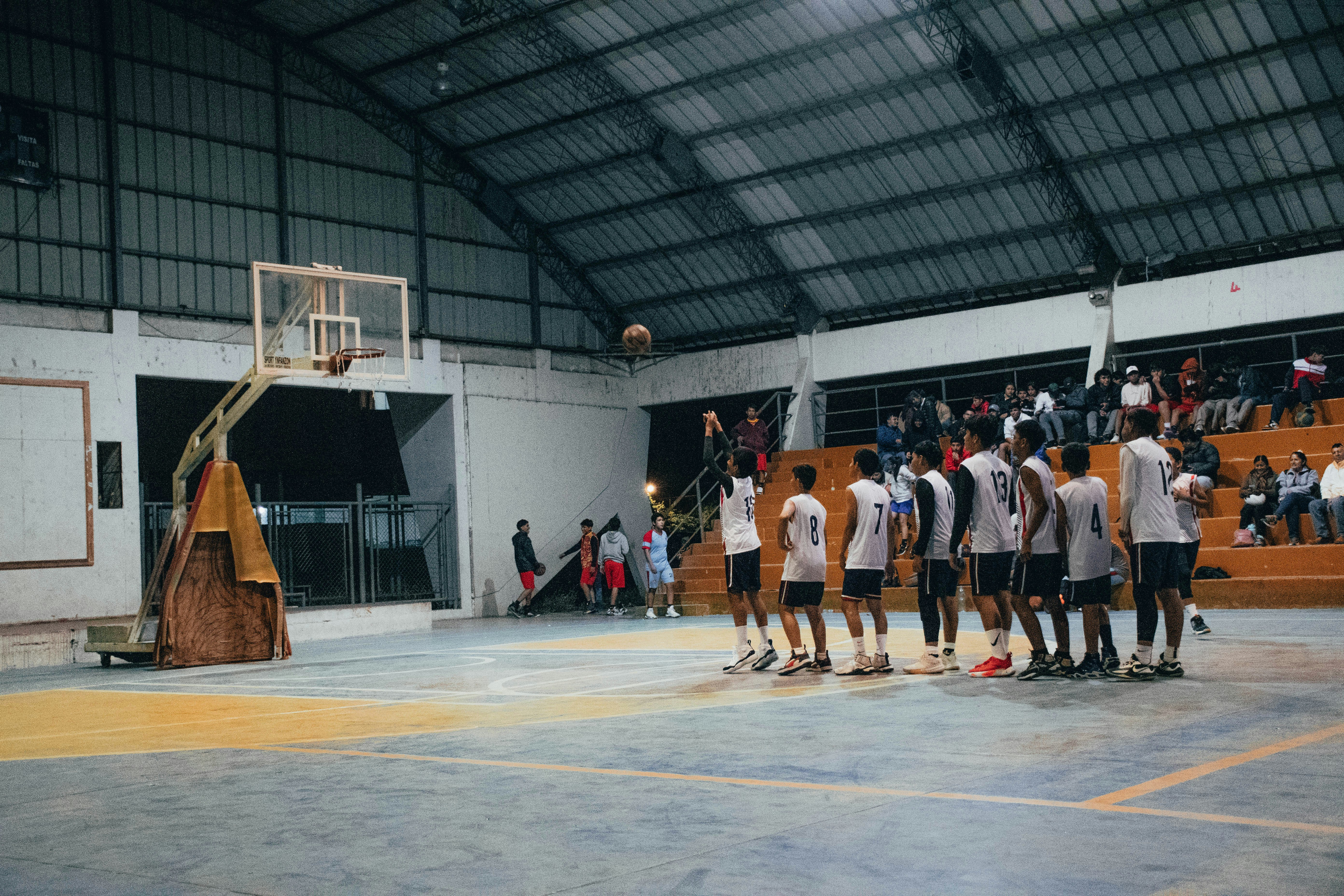 A group of men standing around a basketball court