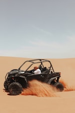A man driving a can - am commander in the desert