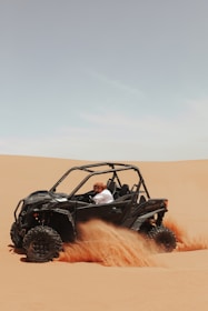 A man driving a can - am commander in the desert