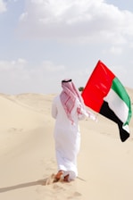 A man holding a flag in the desert