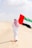 A man walking in the desert holding a flag