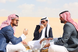 A group of men sitting on top of a sandy beach