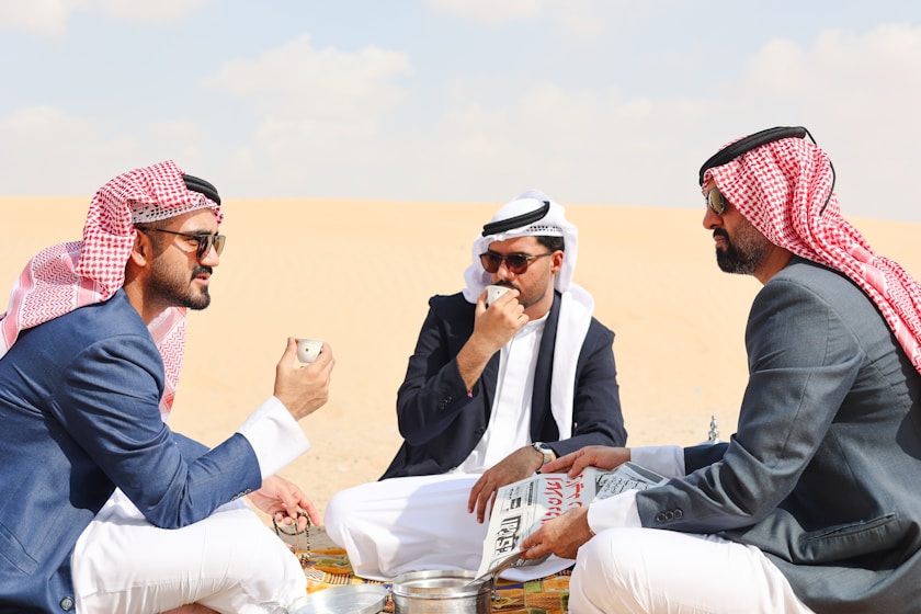 A group of men sitting on top of a sandy beach