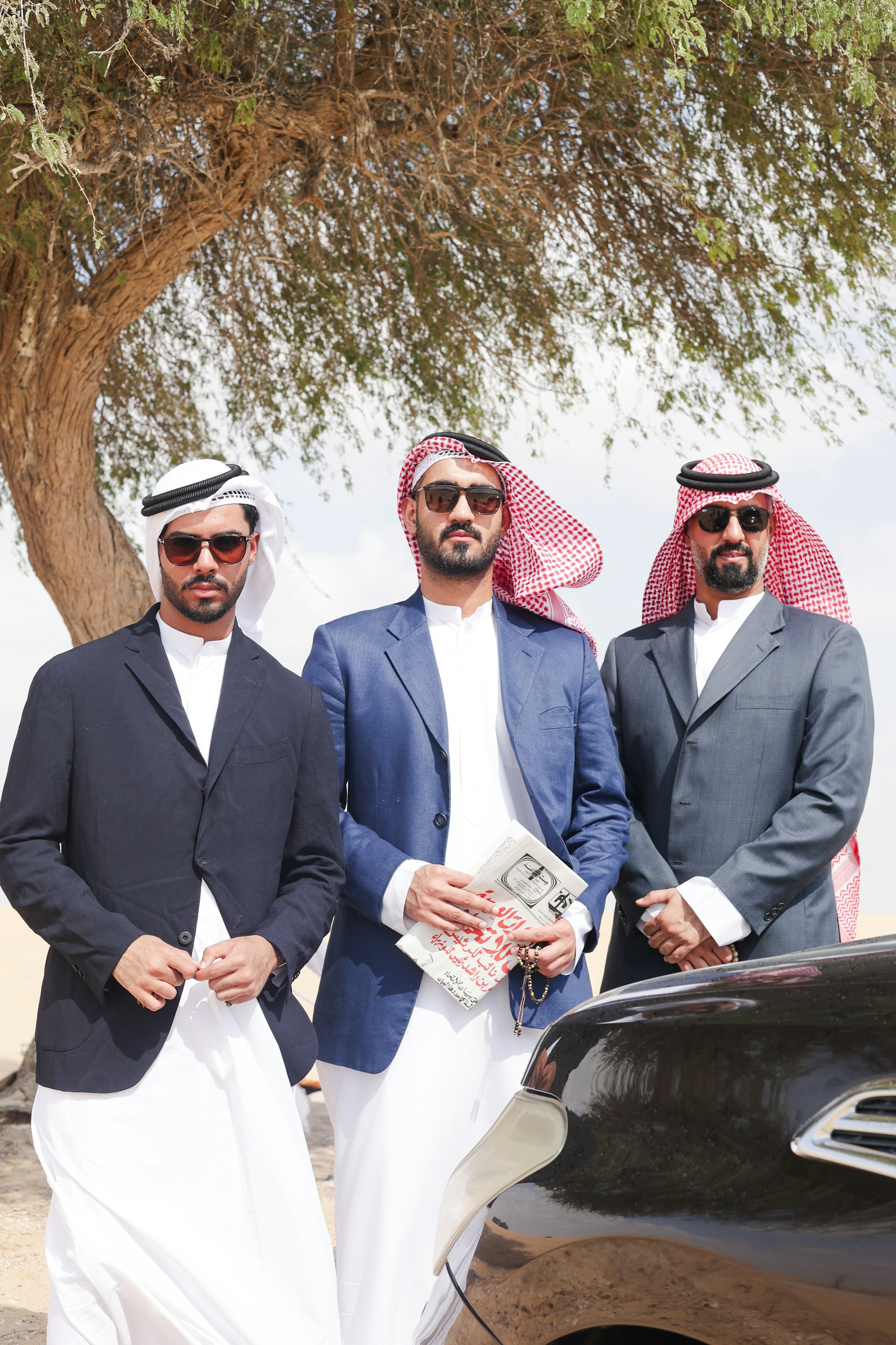 A group of men standing next to a car