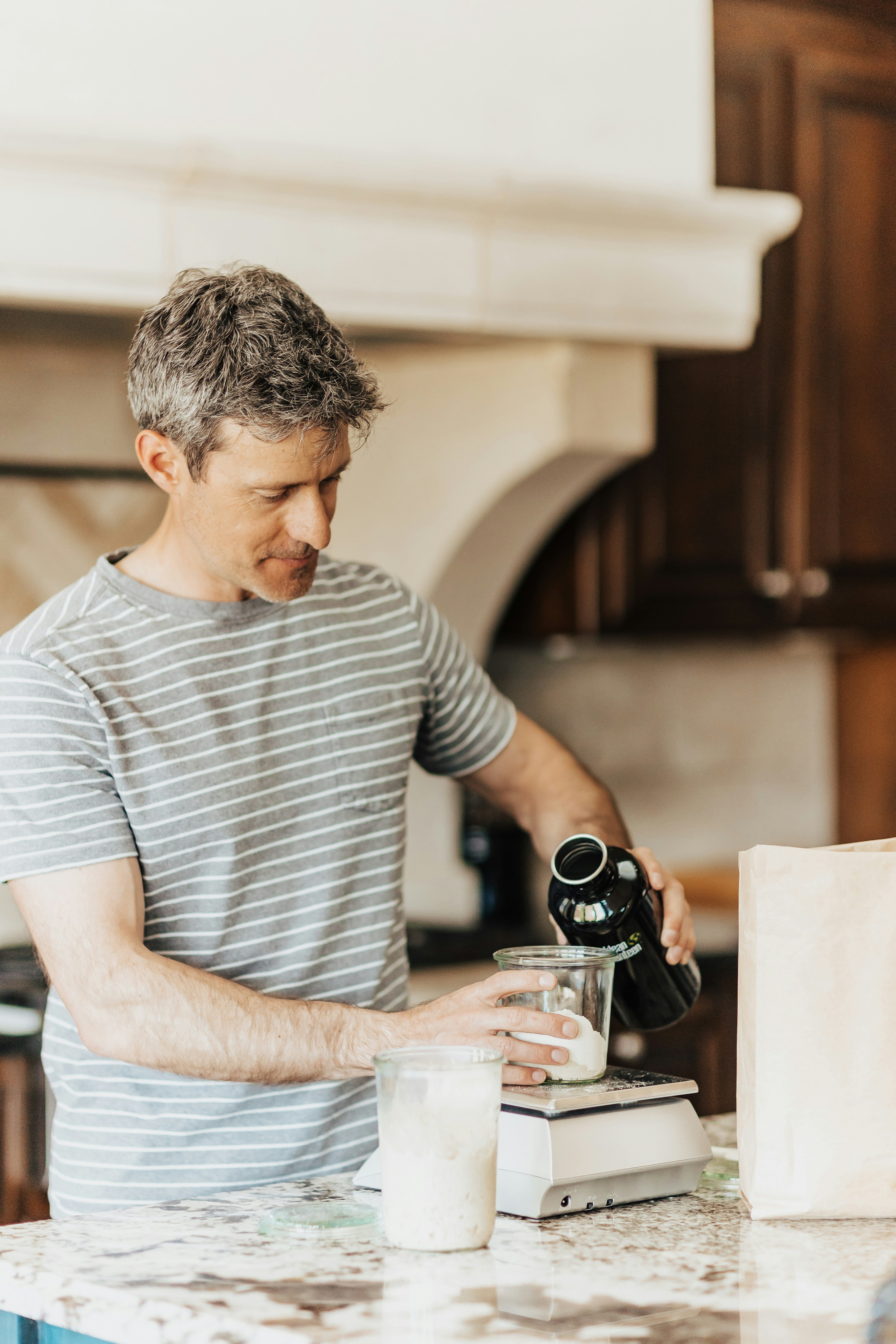 A man standing at a counter with a microscope in his hand