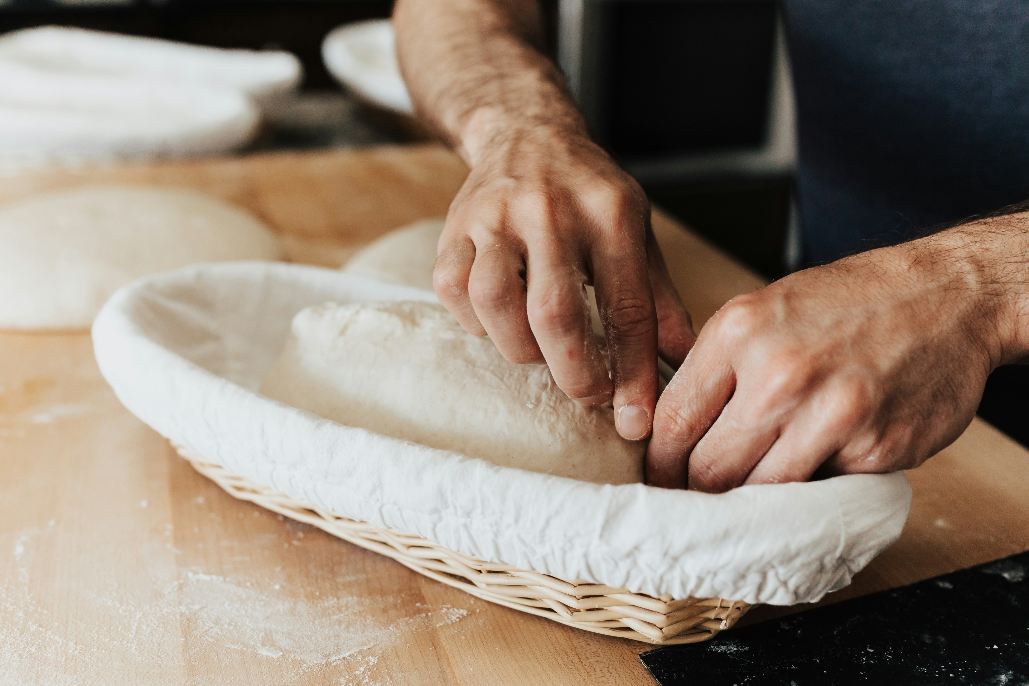 A person is kneading dough into a basket