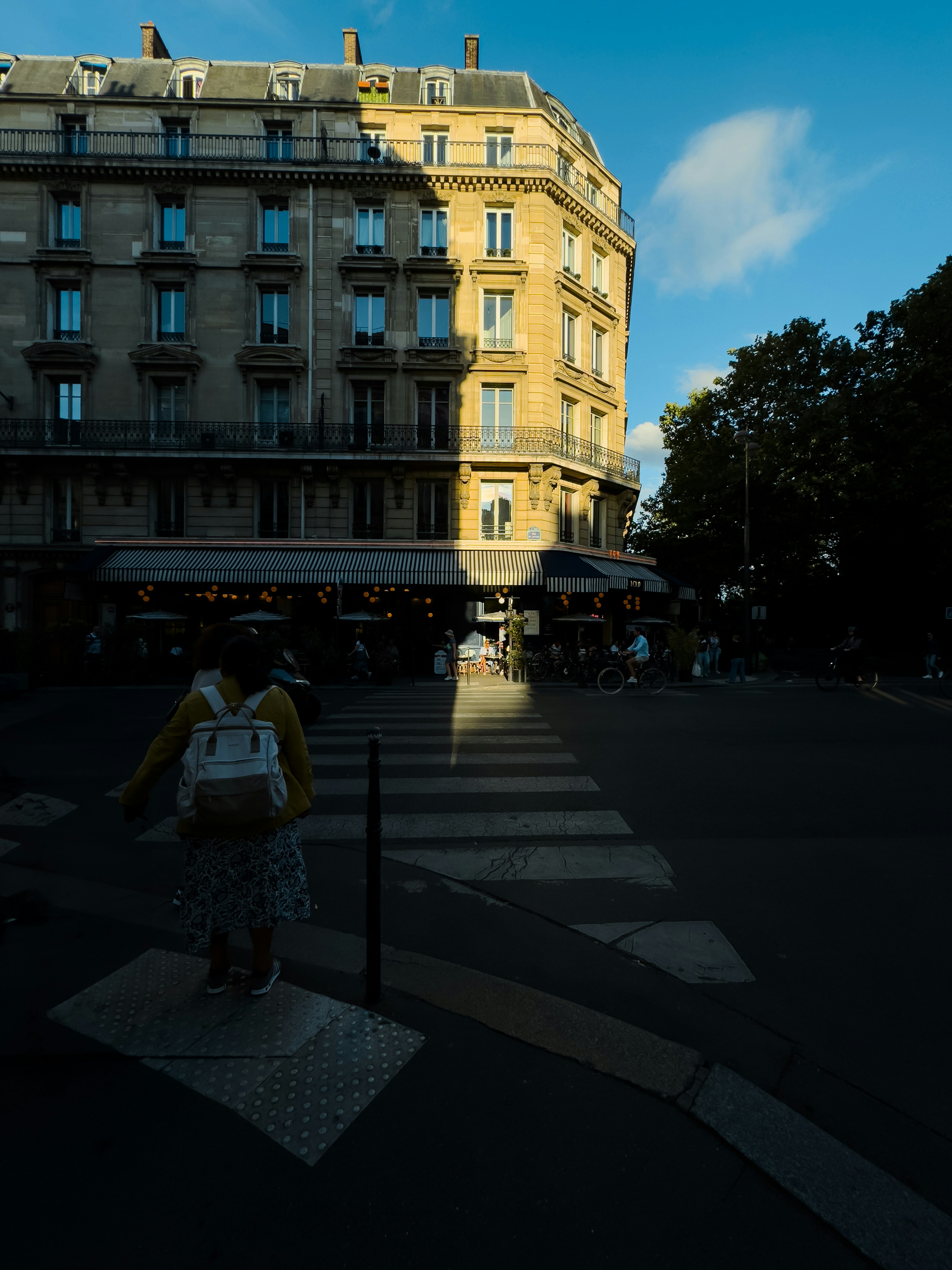 A person crossing a street in front of a tall building
