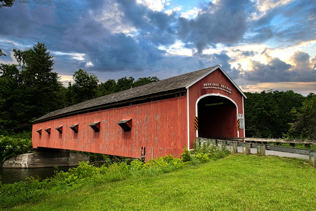 A red covered bridge with a cloudy sky in the background, Historic Covered Bridge, Buskirk, NY.