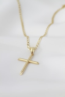 A gold necklace with a cross on it