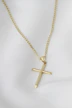 A gold cross necklace on a mannequin