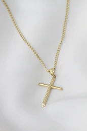 A gold cross necklace on a mannequin