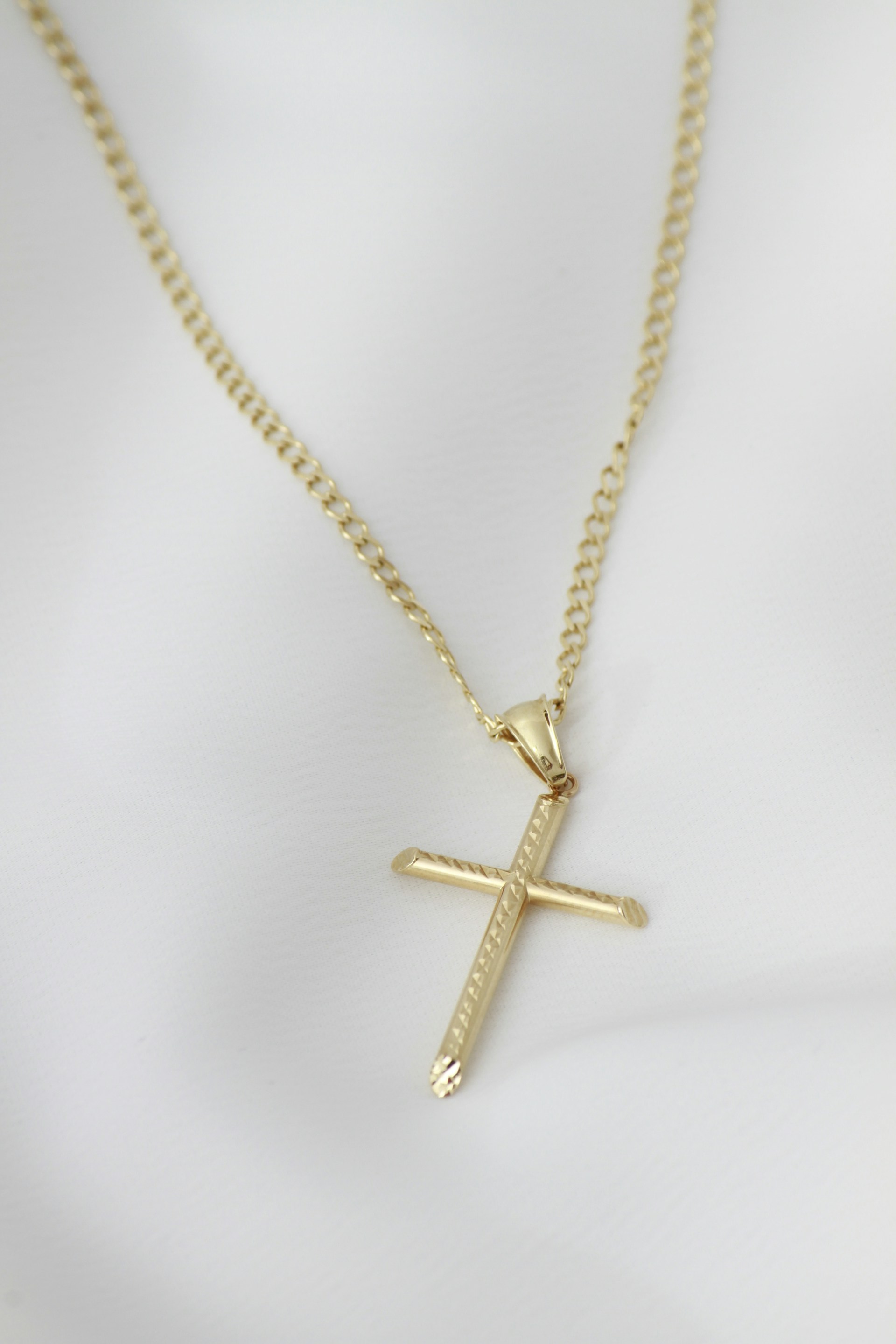 A gold cross necklace on a mannequin