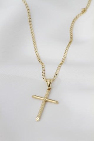 A gold cross necklace on a mannequin