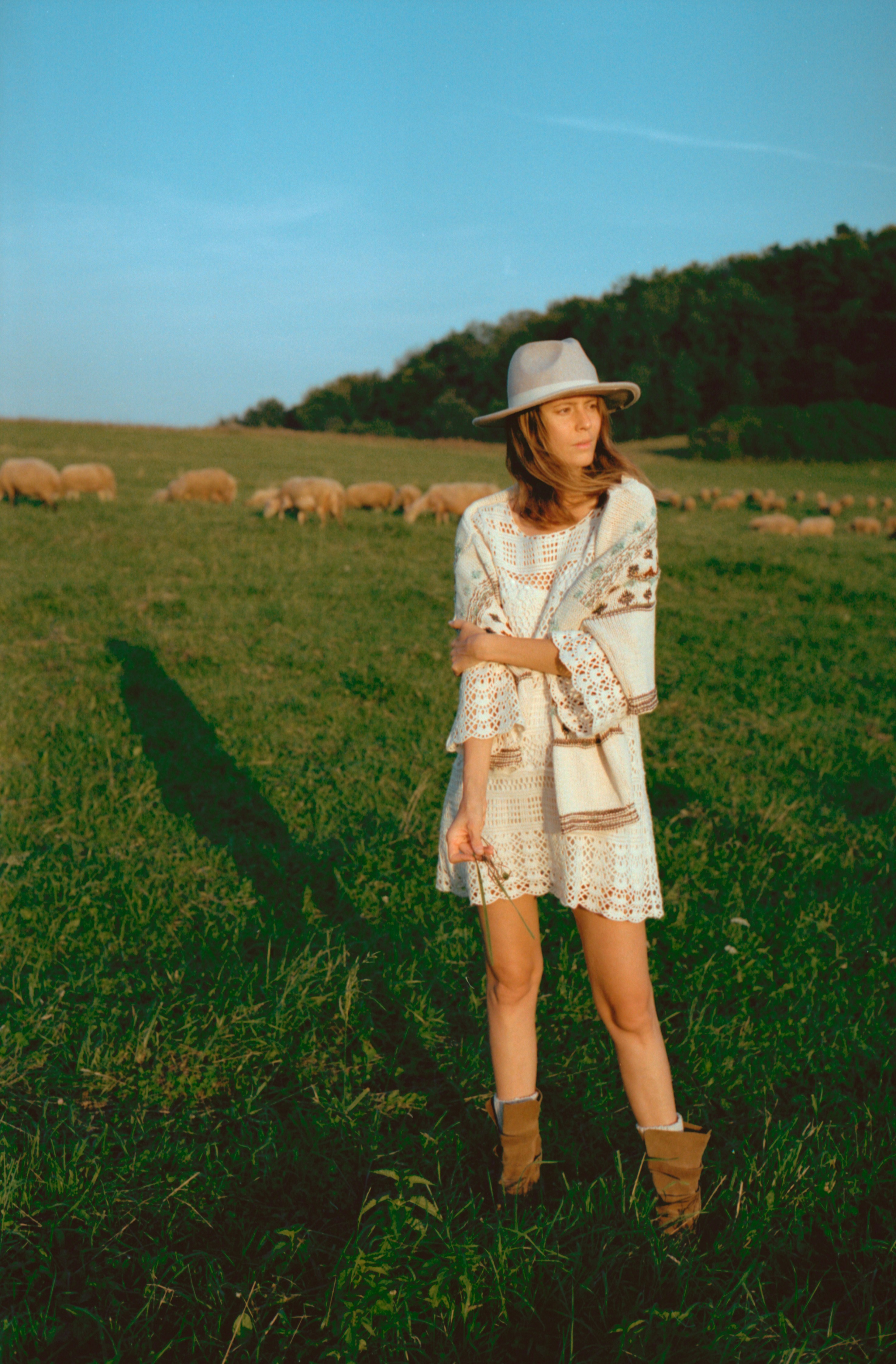 A woman standing in a field with sheep in the background