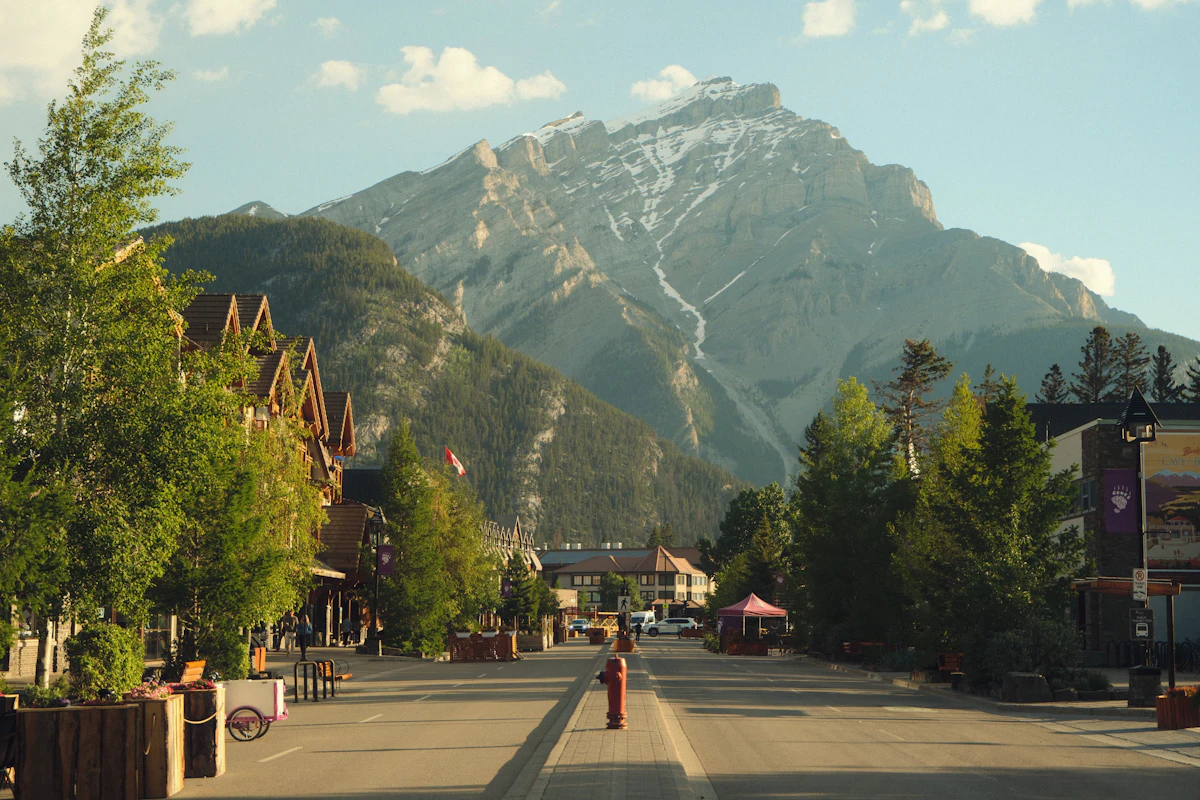 Banff Avenue in early morning light, with a bare rock mountain rising over the town