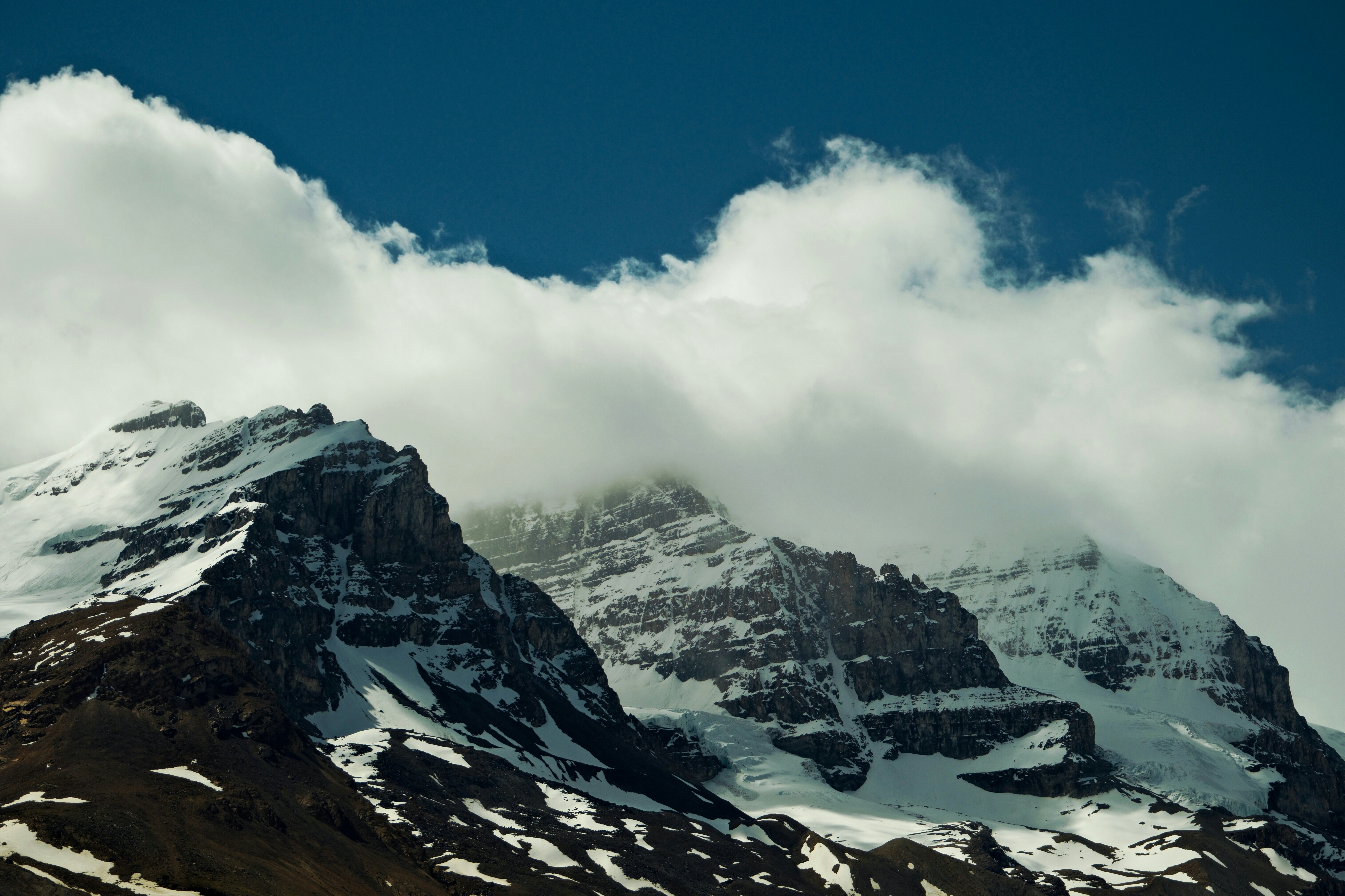 A mountain covered in snow under a cloudy sky