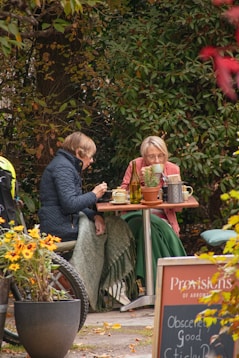 A couple of women sitting at a table outside