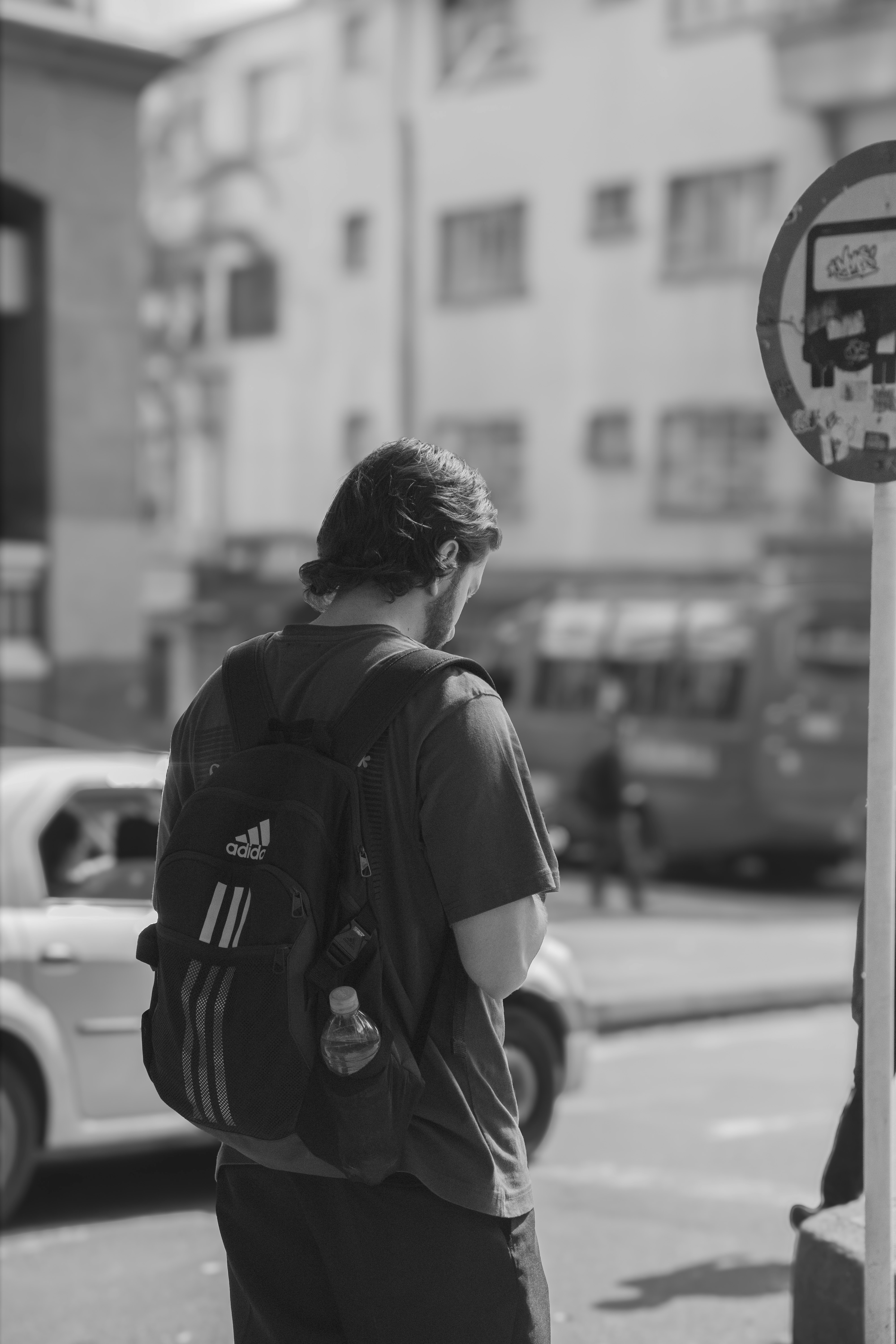 A man with a backpack standing next to a parking meter