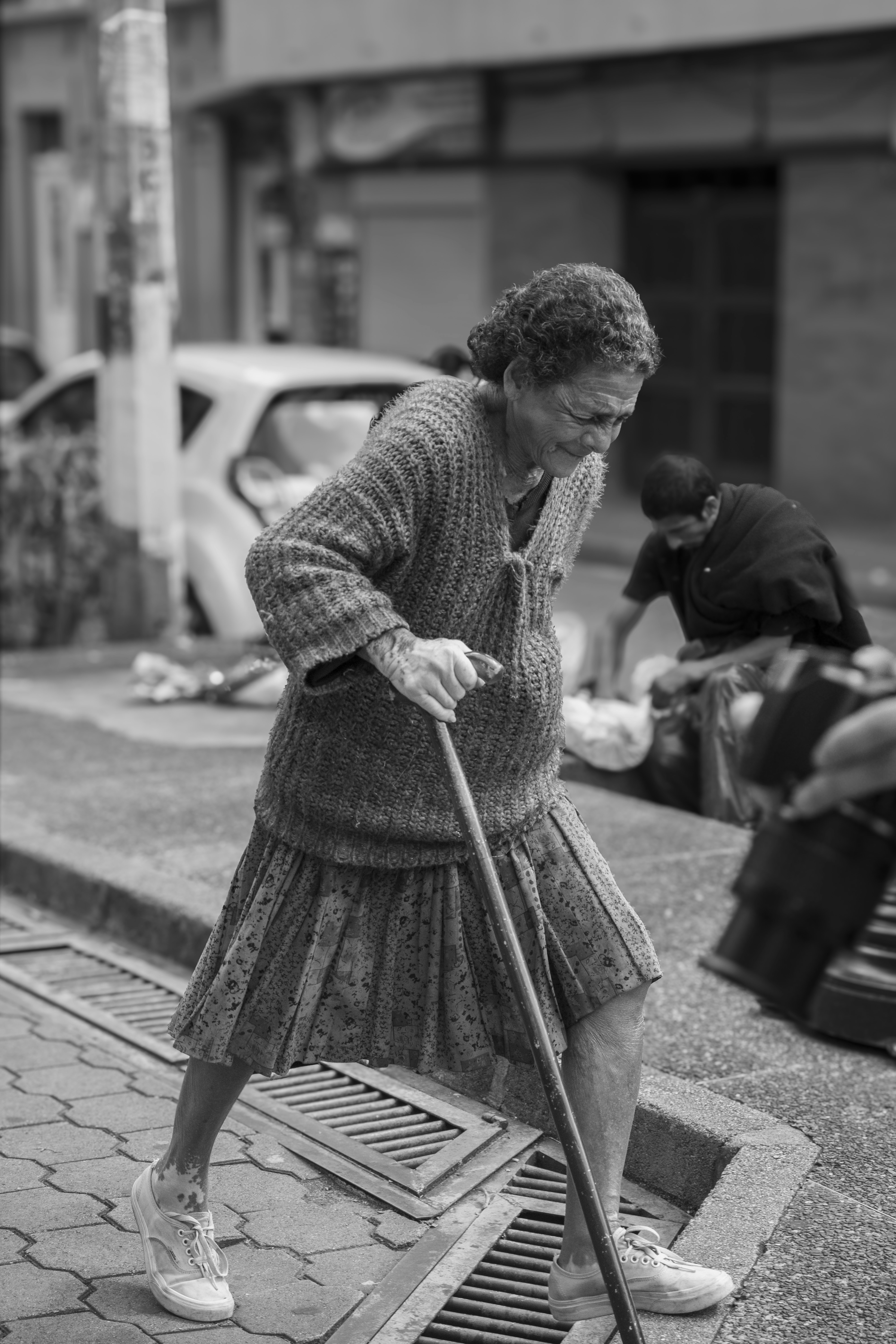 通りを掃除する女性の白黒写真