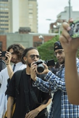 A group of people standing around each other taking pictures