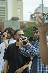 A group of people standing around each other taking pictures