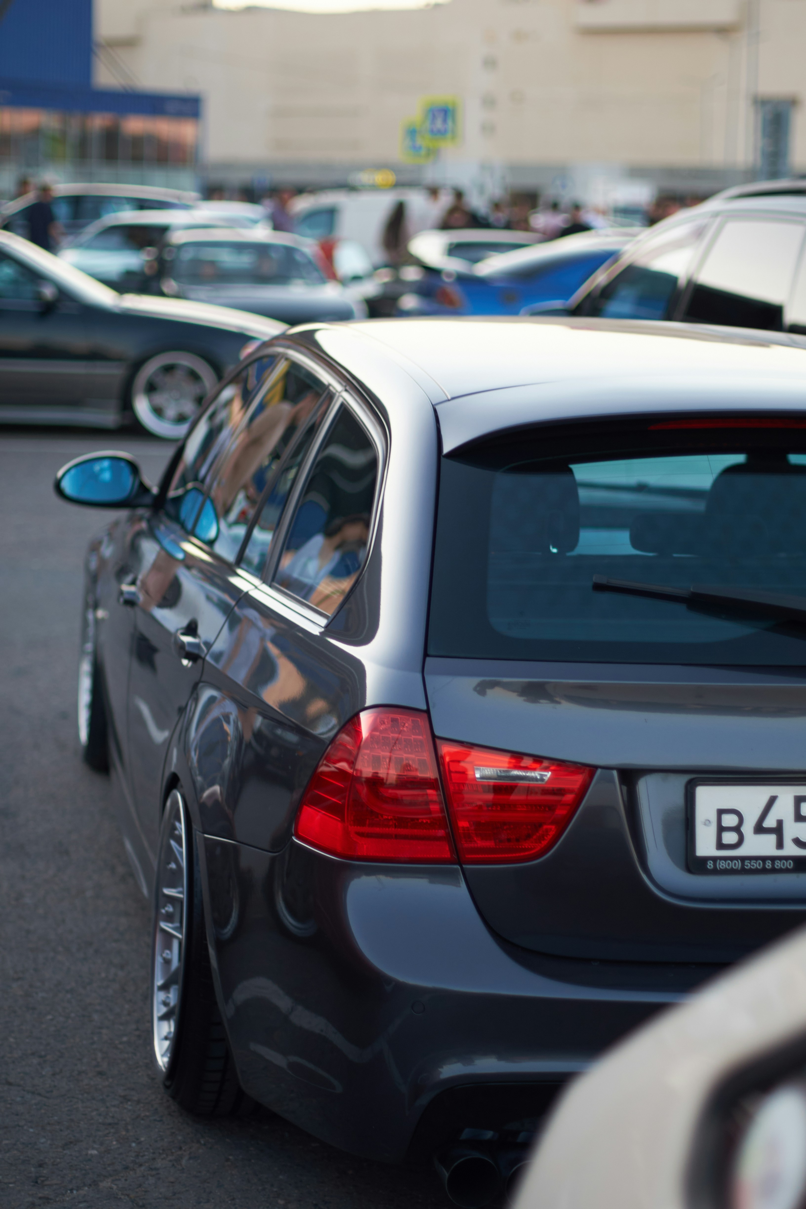 A grey car parked in a parking lot next to other cars