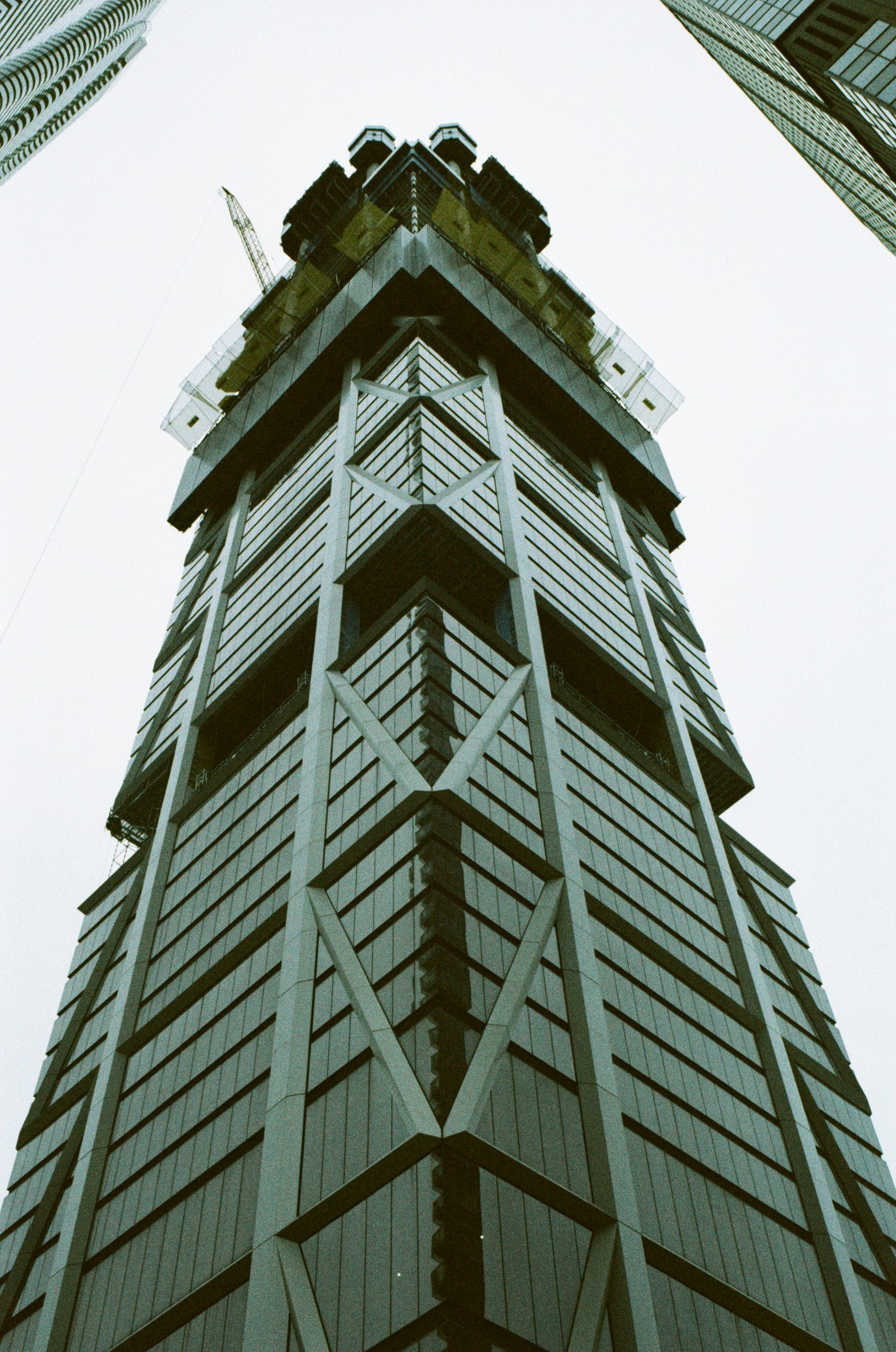 Looking up at a tall building with a crane on top