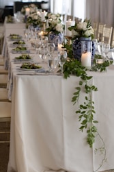 A long table with white and blue flowers and greenery