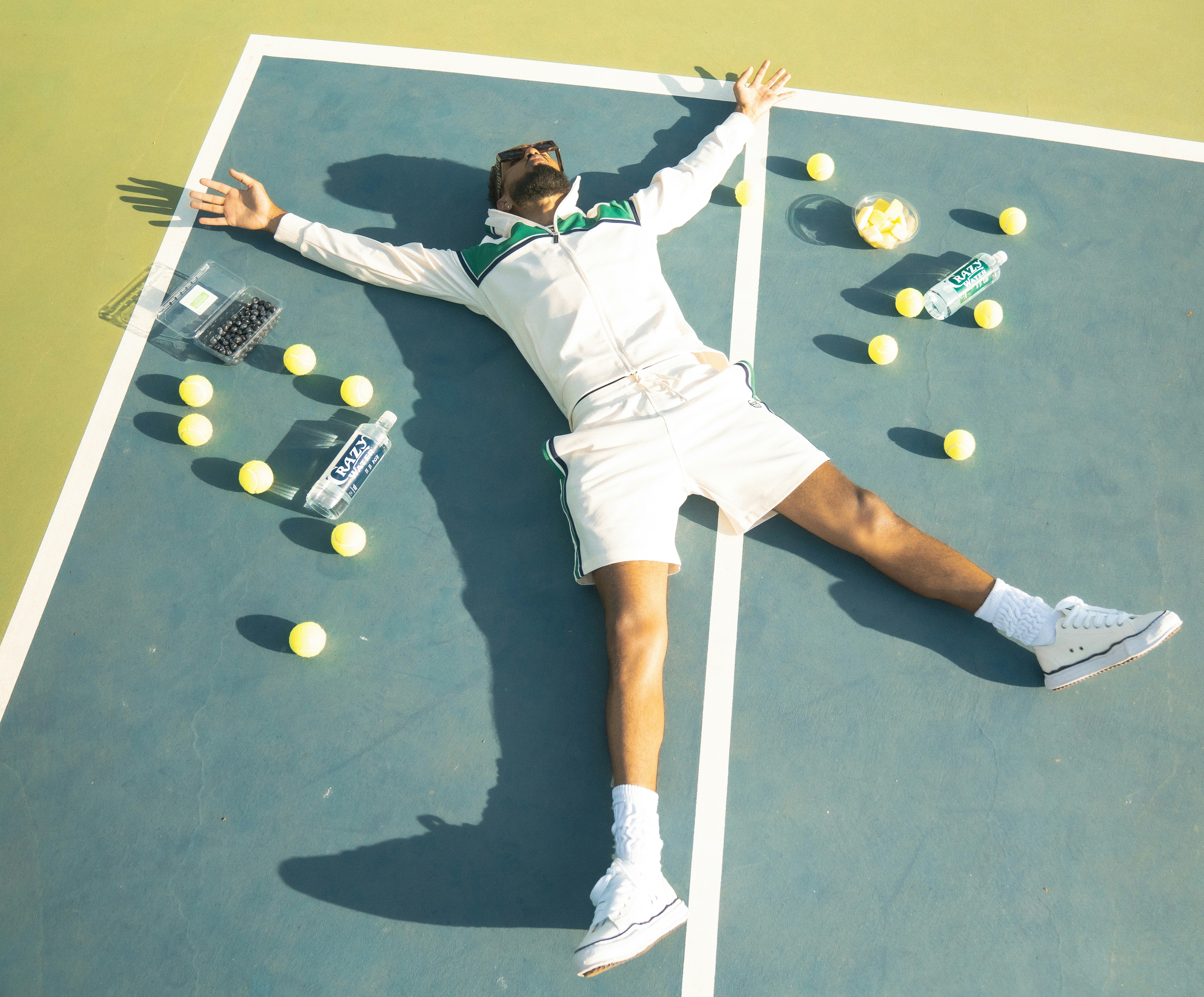A man laying on a tennis court holding a racquet