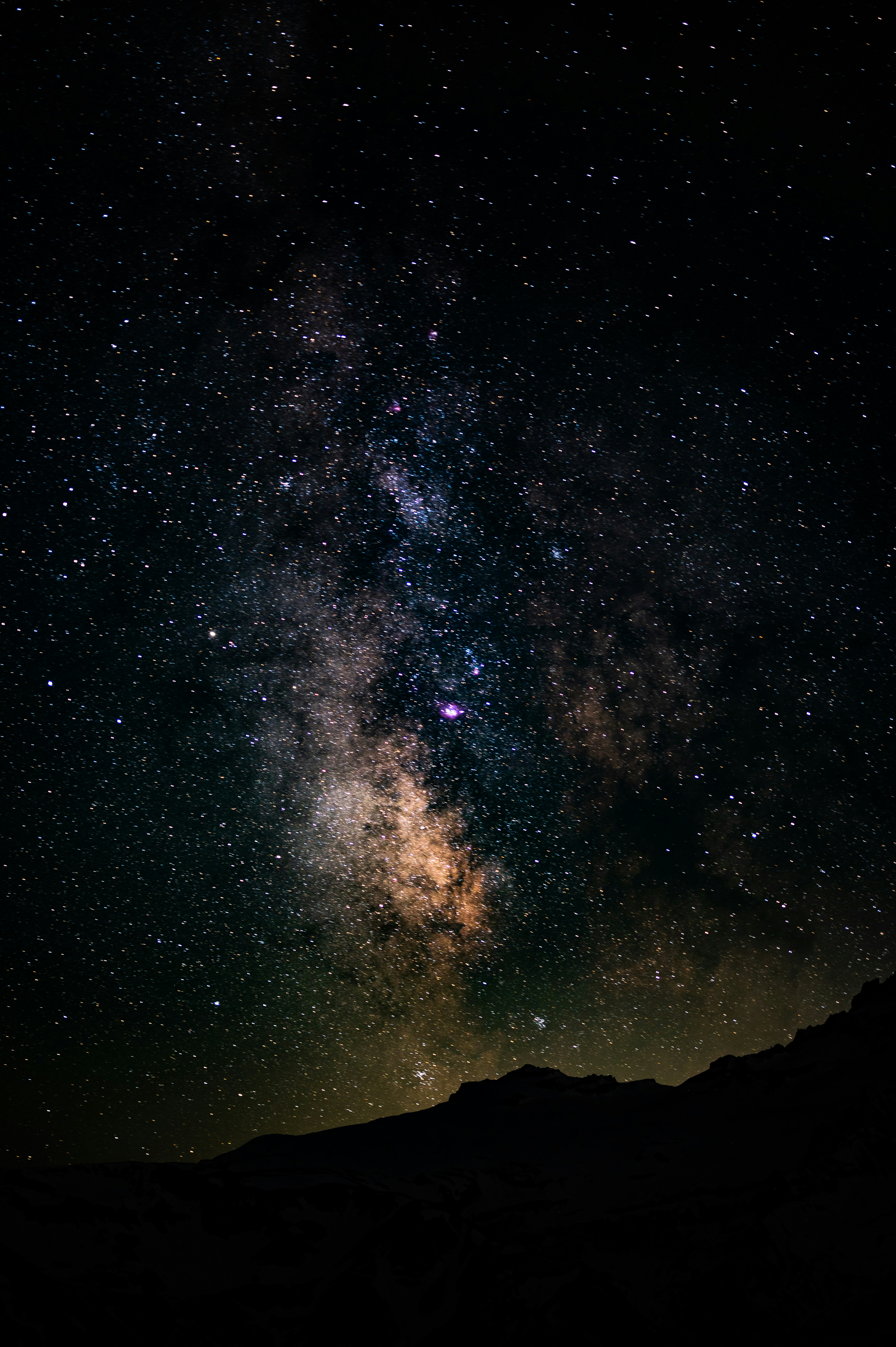 Milky Way arching over the volcanic caldera of La Palma at night, with the Roque de los Muchachos observatory silhouetted against a pristine dark sky