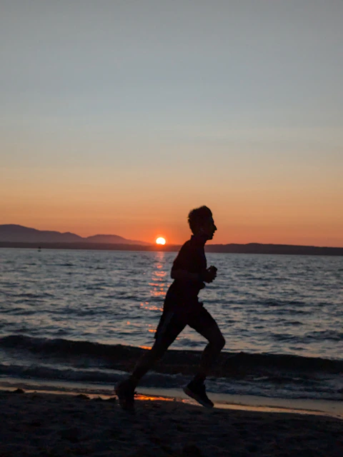 A man running on the beach at sunset