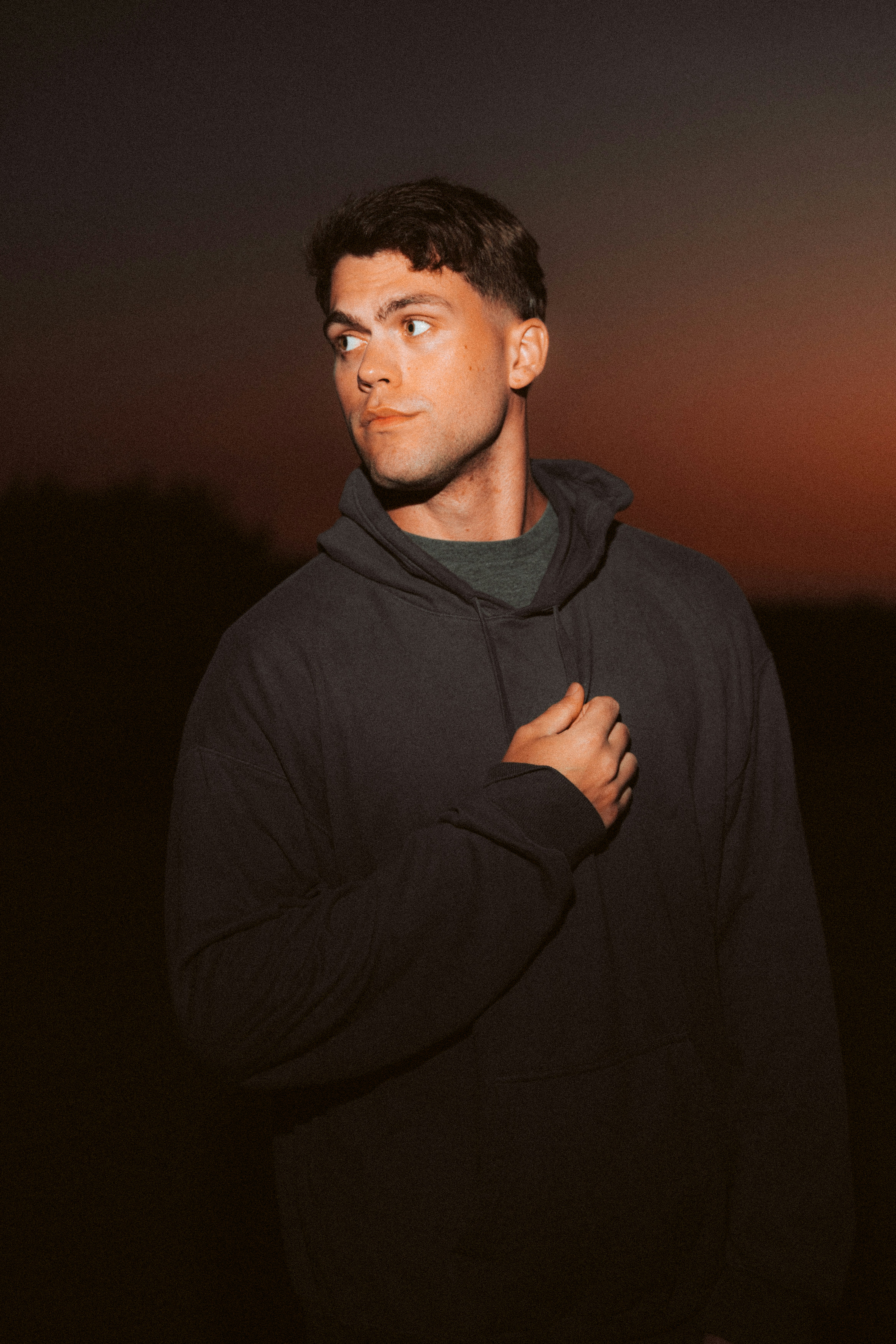 A man in a black hoodie standing in the dark