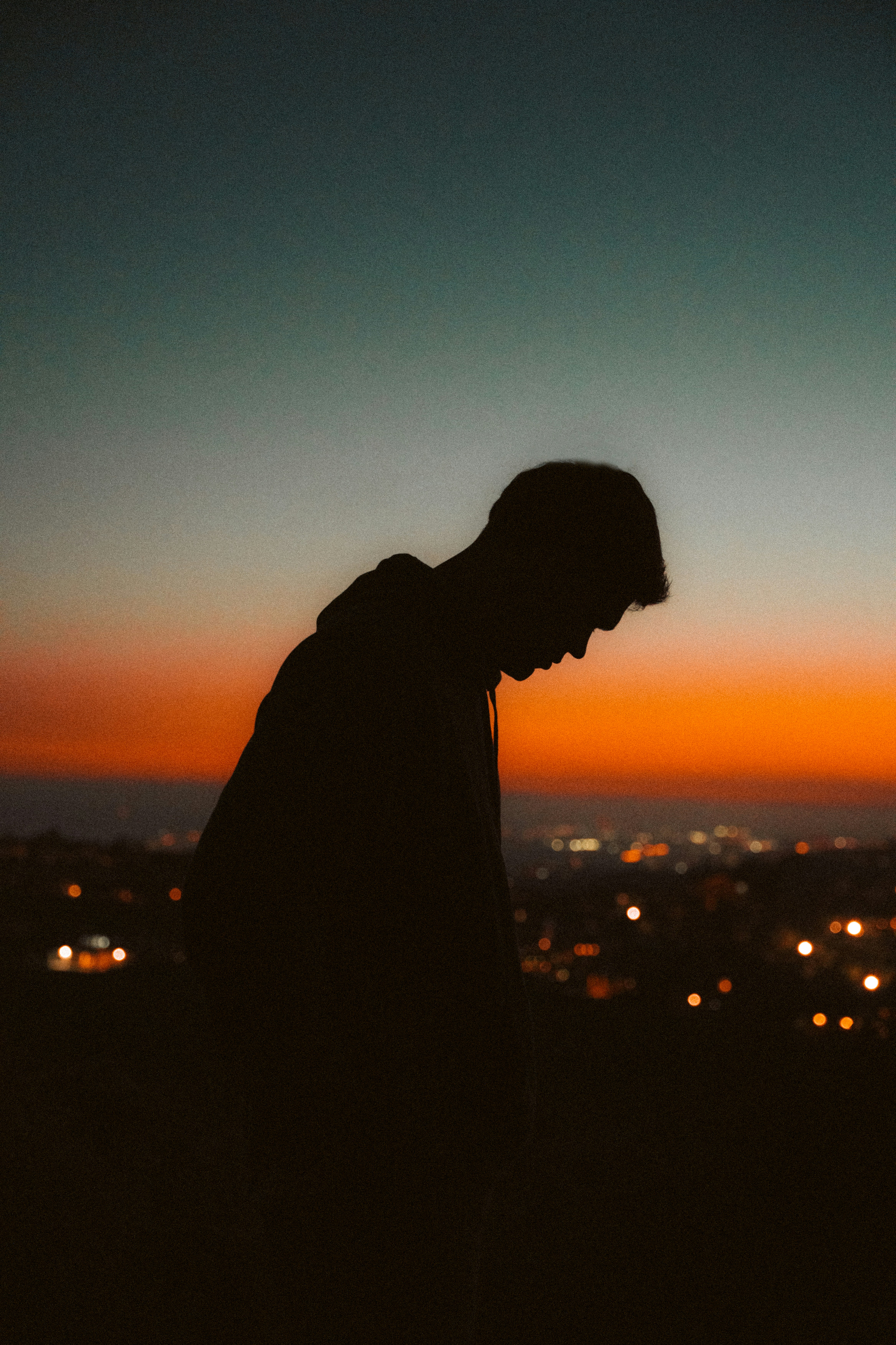A man standing on top of a hill next to a city